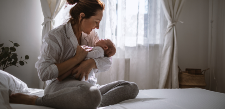 Mother holding kids in her hands, sitting on the bed